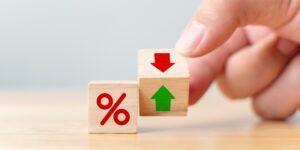 A hand holding a wooden block with a down arrow to symbolize lower pawn shop interest rates