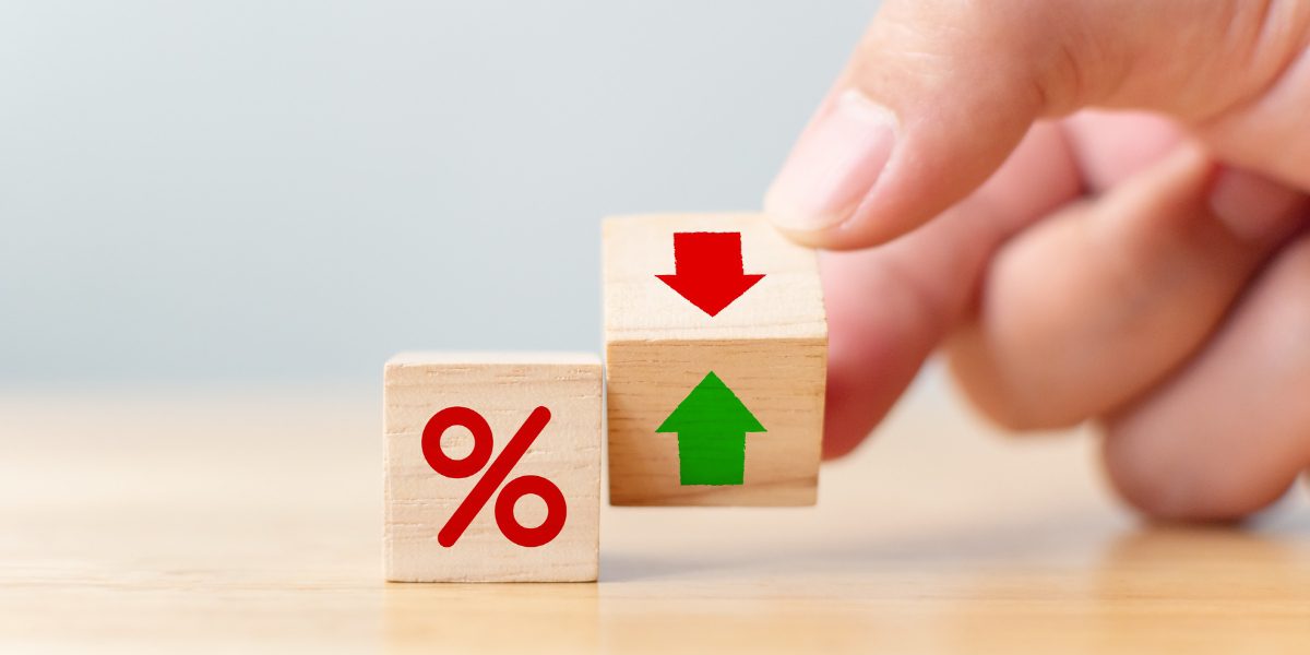 4 A hand holding a wooden block with a down arrow to symbolize lower pawn shop interest rates