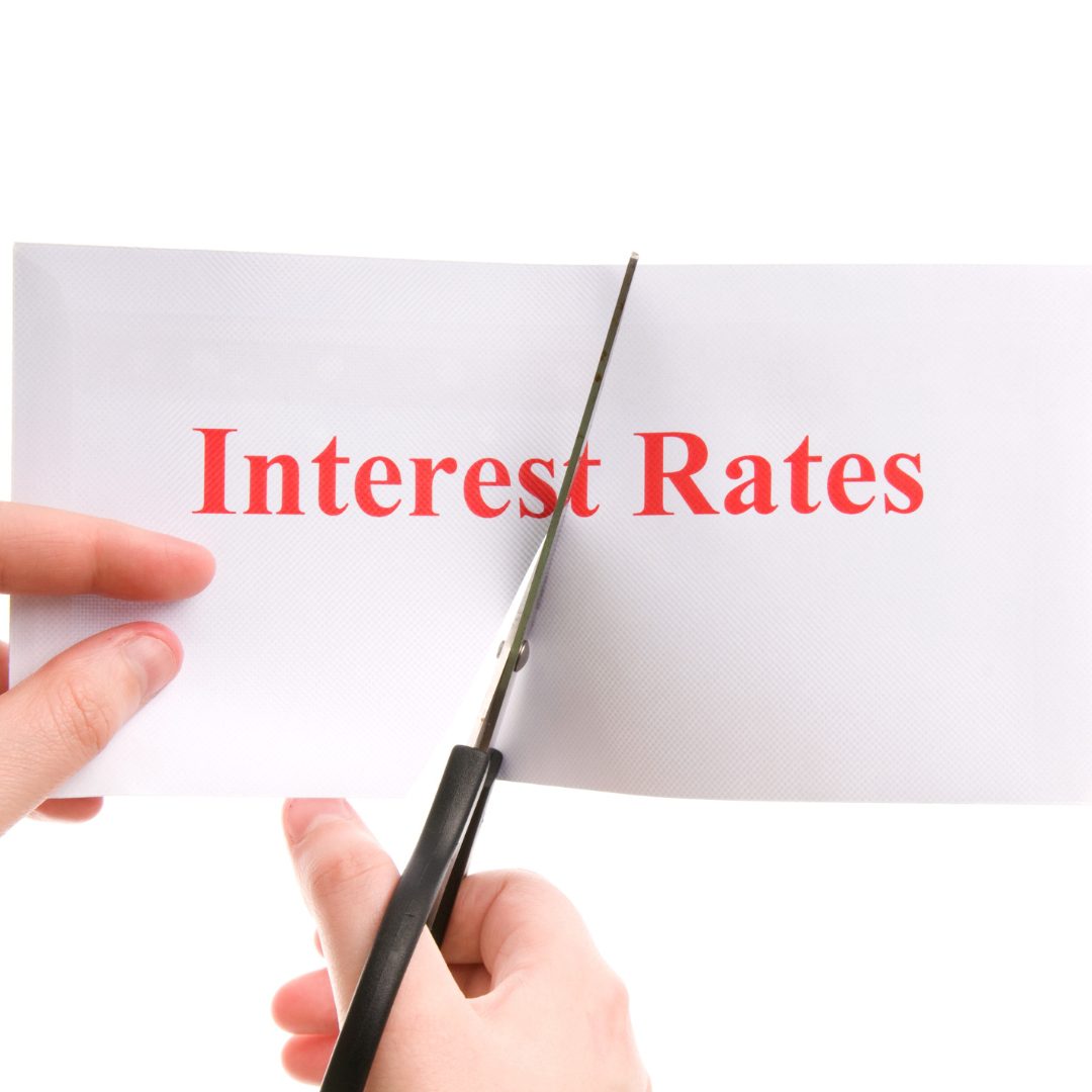 A pair of hands cutting interest rates written on a piece of paper in half