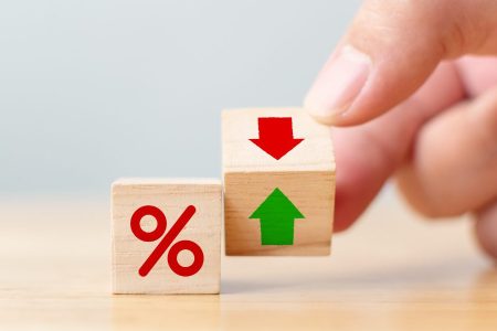 A hand holding a wooden block with a down arrow to symbolize lower pawn shop interest rates