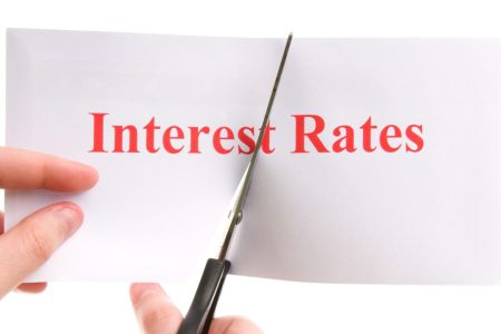 A pair of hands cutting interest rates written on a piece of paper in half
